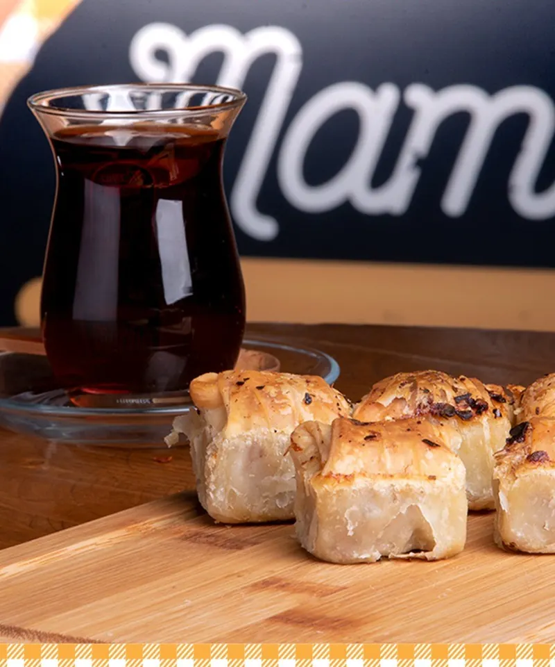 A glass of black tea next to mantia on a board