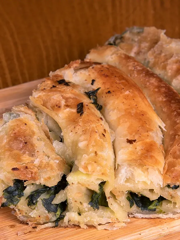 A spinach pite slice on a wooden board